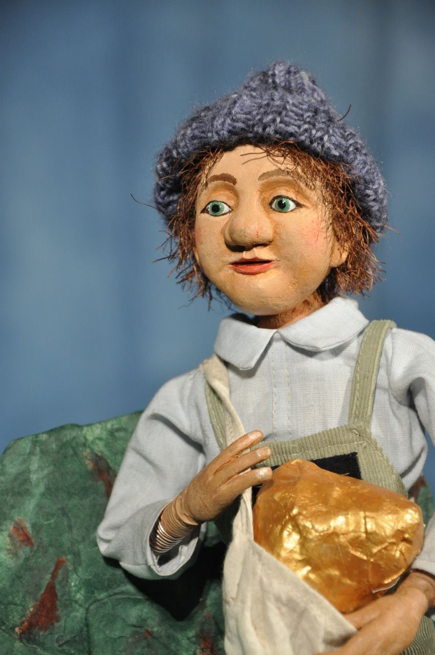 Eine Puppe mit grünen Augen liegt unter einem Stofftier