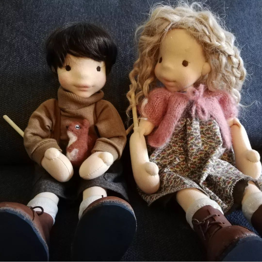 Eine Jungen- und eine Mädchenpuppe sitzen nebeneinander auf einer Couch