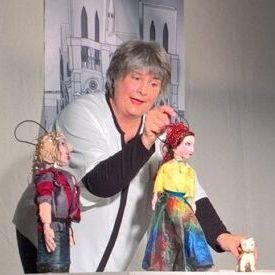 Eine Frau spielt mit zwei Puppen und einer Katze.