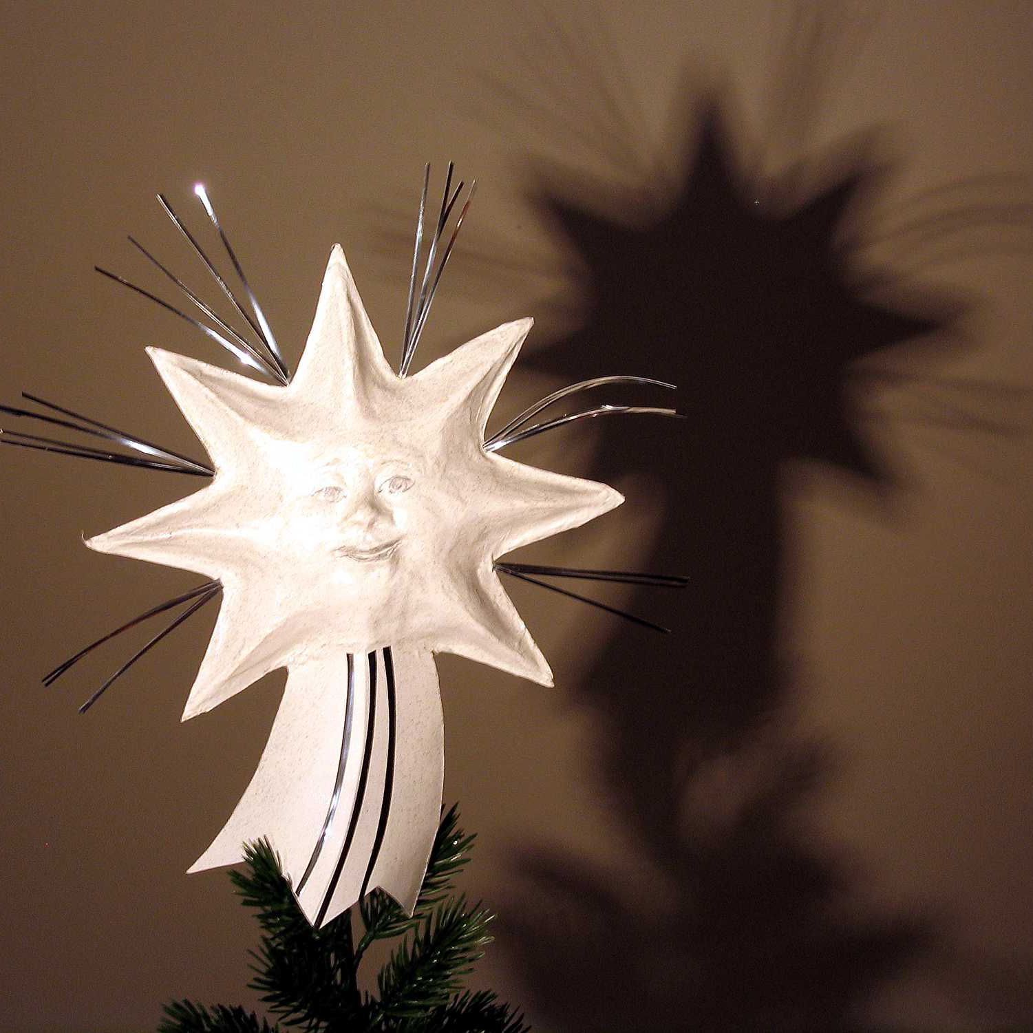 Ein Stern mit einem Gesicht darauf ist auf der Spitze eines Weihnachtsbaumes