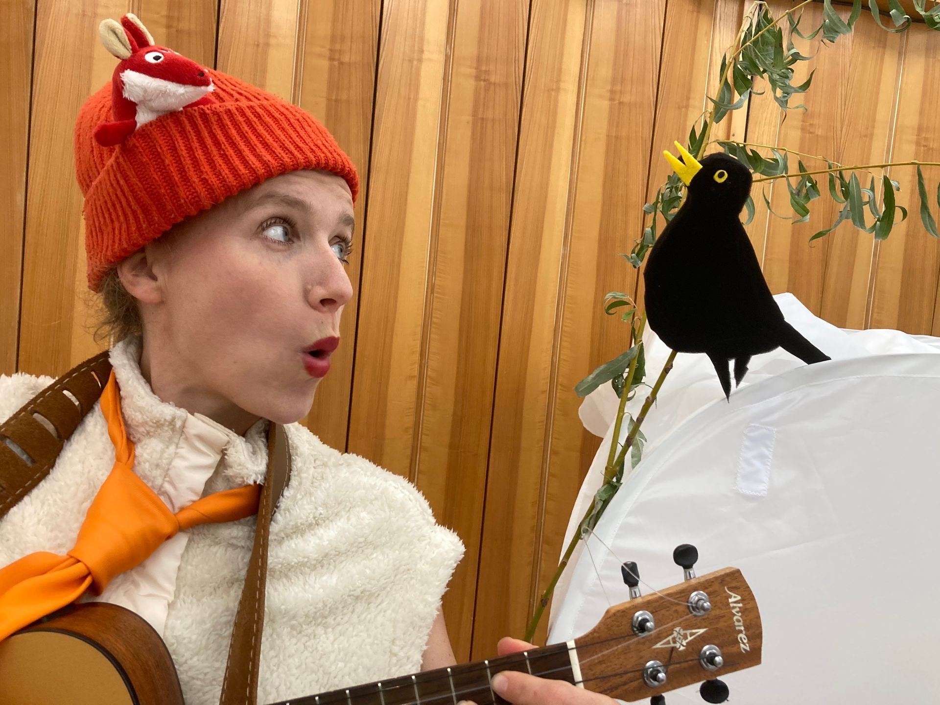 Eine Frau, die neben einem schwarzen Vogel Gitarre spielt