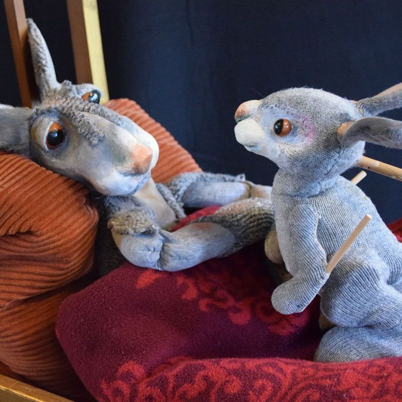 Ein ausgestopfter Esel und ein ausgestopfter Hase liegen auf einem Bett