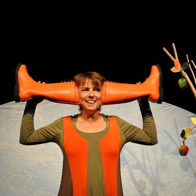 Eine Frau hält ein Paar orangefarbene Stiefel auf dem Kopf