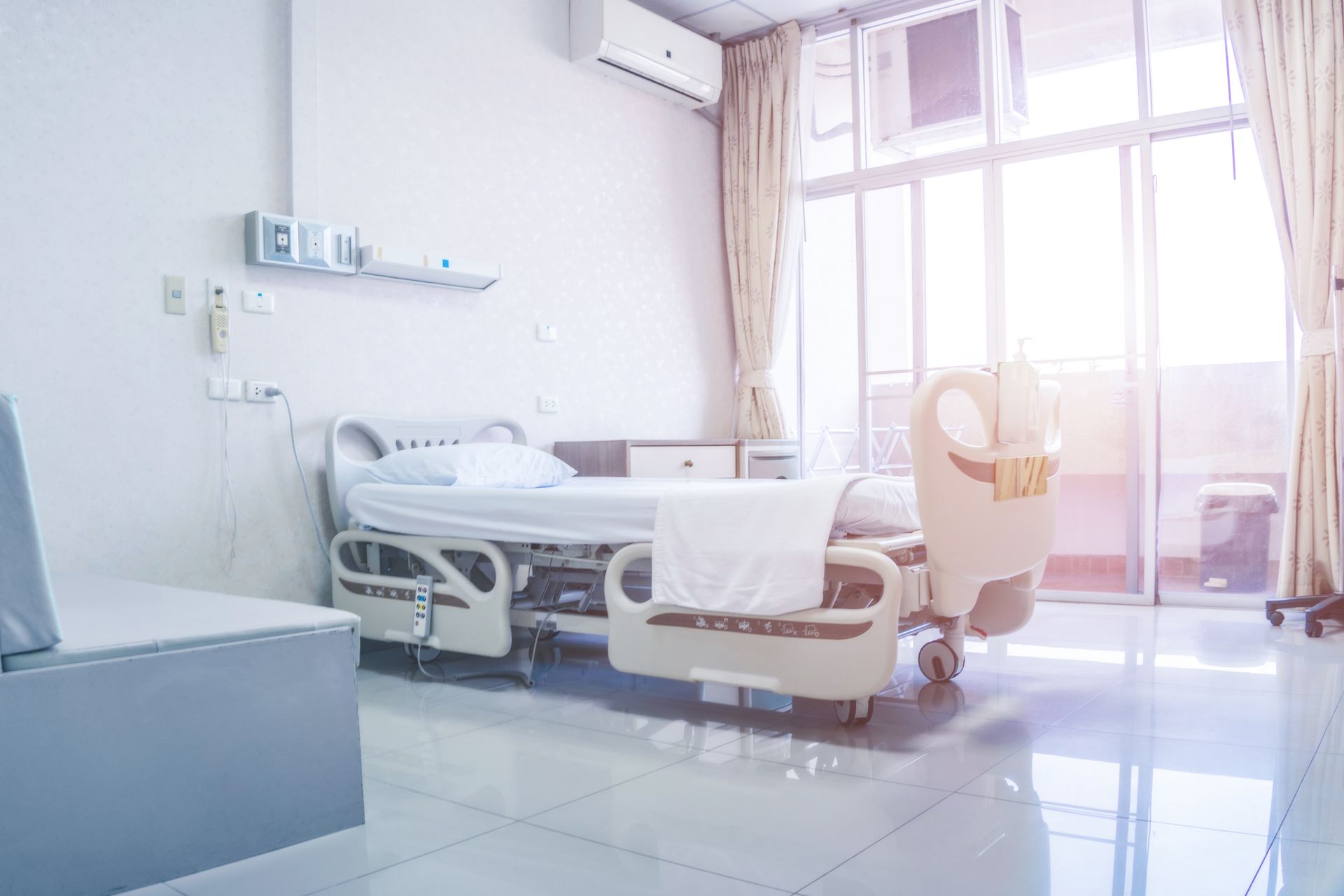 Bright hospital room with a bed, a window, and a bench. Bright hospital room with a bed, a window, and a bench.