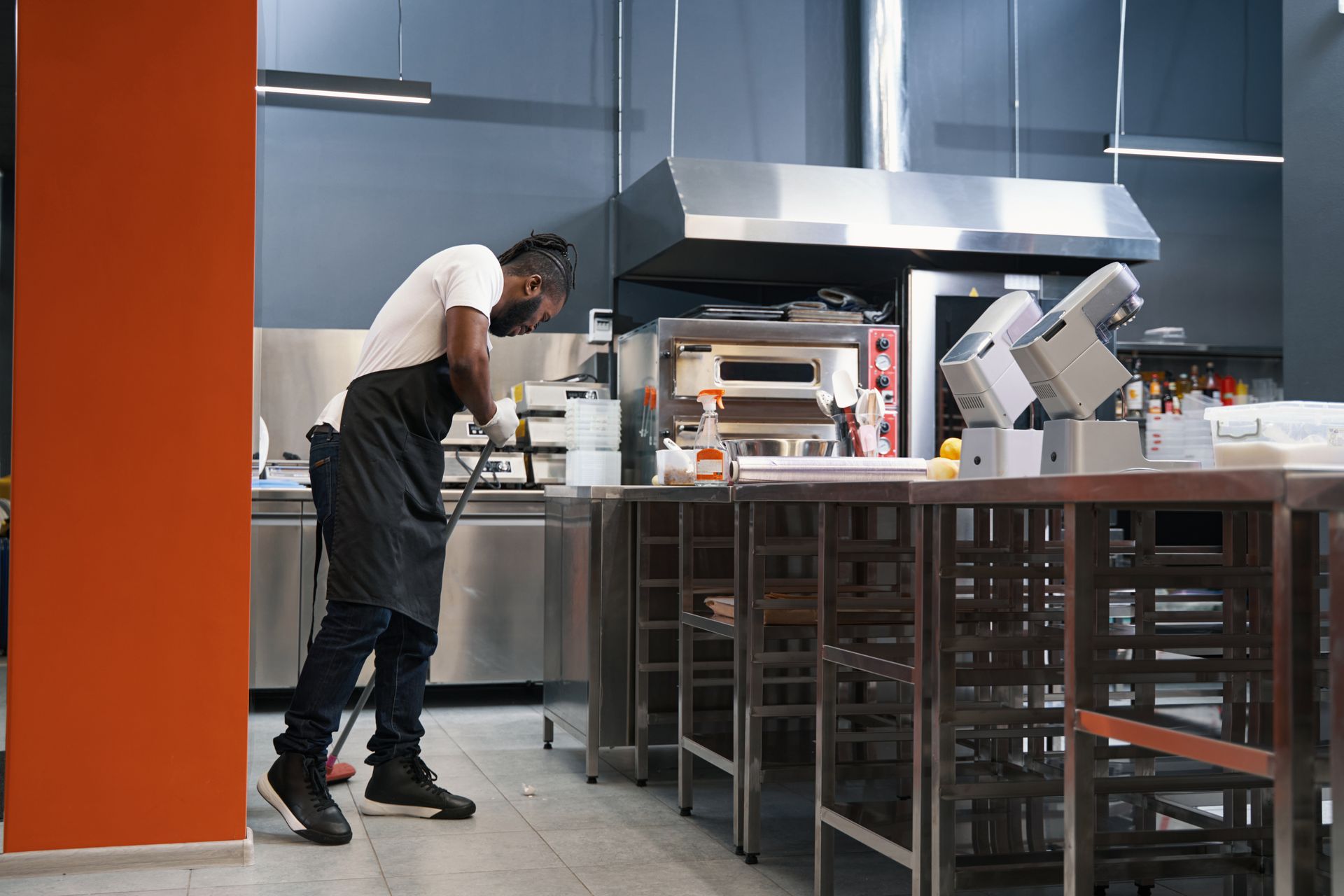 A person wearing an apron cleans a commercial kitchen.
