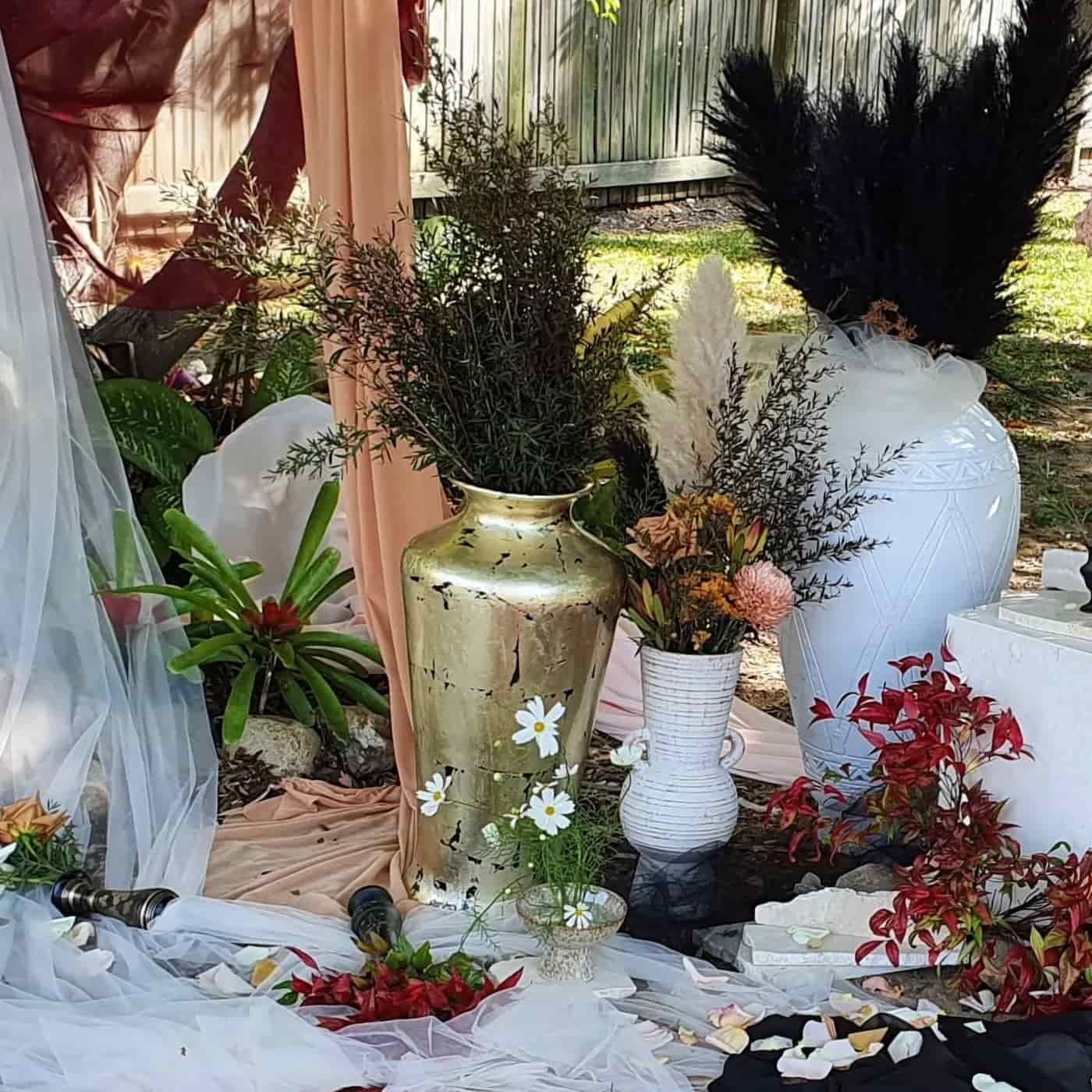 A Table Topped With Vases Filled With Flowers And Feathers — Lynda Ross Marriage Celebrant In Ingham, QLD
