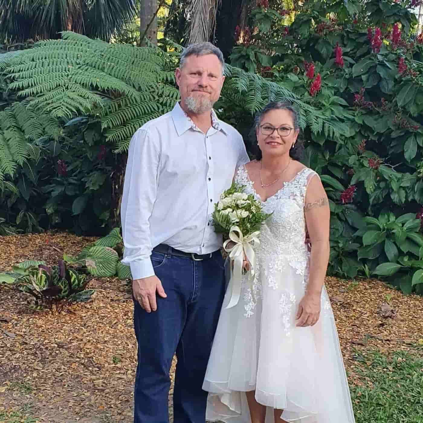 A Man And A Woman Are Posing For A Picture In Front Of A Bush — Lynda Ross Marriage Celebrant In Charters Towers, QLD