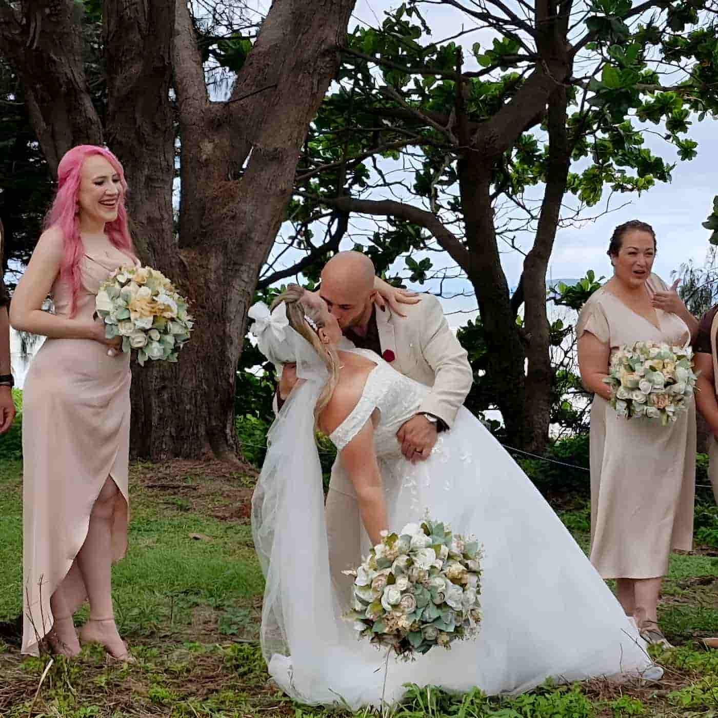 A Bride And Groom Kissing In Front Of Their Bridesmaids — Lynda Ross Marriage Celebrant In Hervey Range, QLD