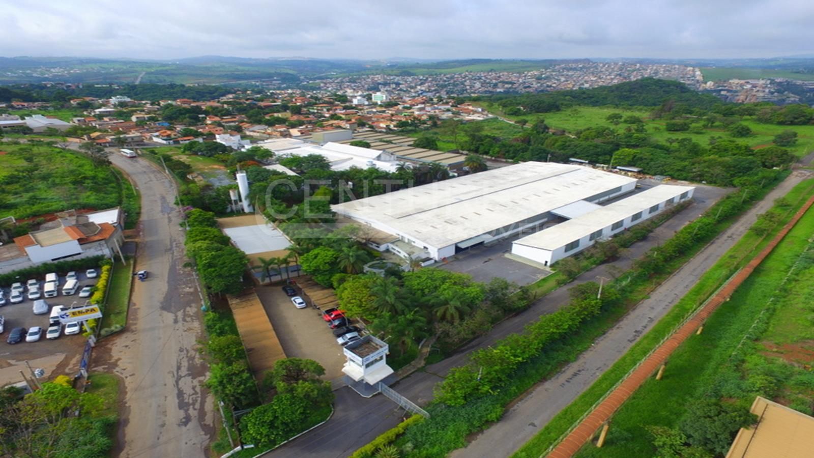 Uma vista aérea de um grande edifício branco cercado por árvores e uma estrada.