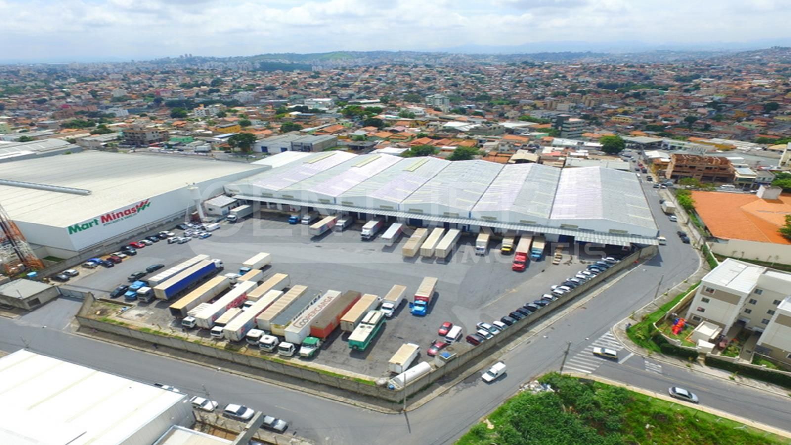 Uma vista aérea de um grande armazém com caminhões estacionados na frente dele.