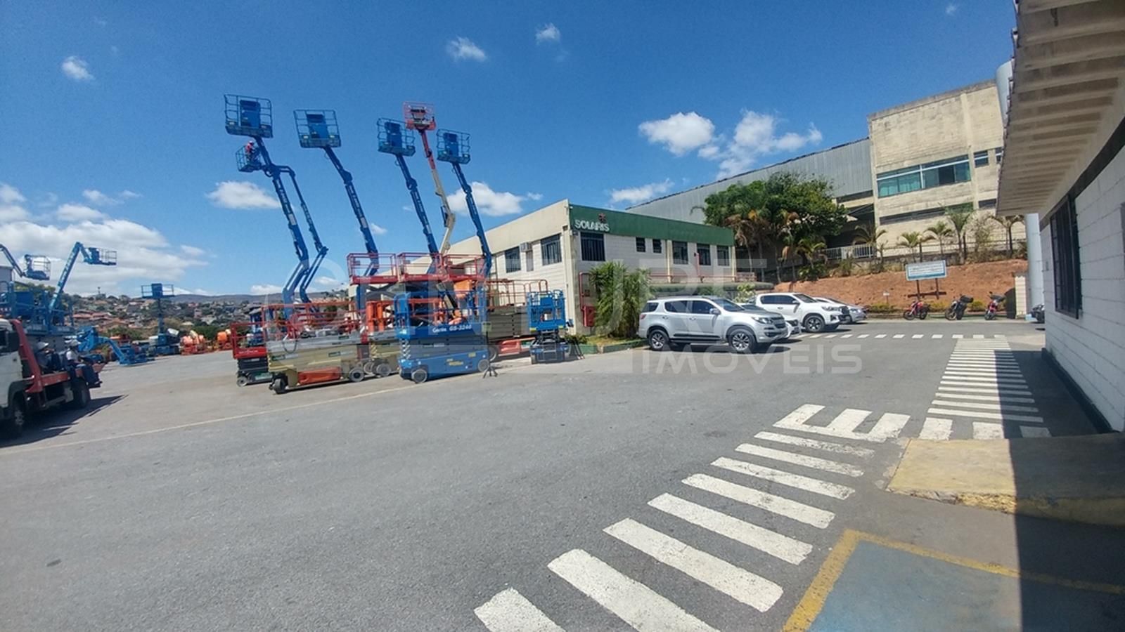 Muitos veículos estão estacionados em um estacionamento em frente a um prédio.