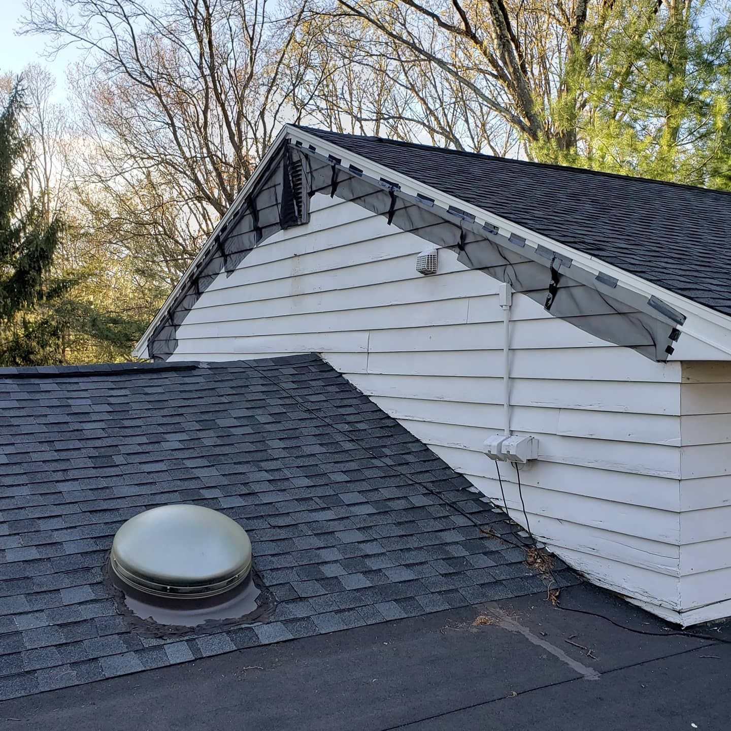 A white house with a black roof and a skylight on the roof.
