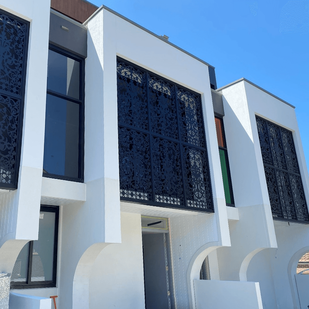 Modern white building facade with tall dark decorative window panels