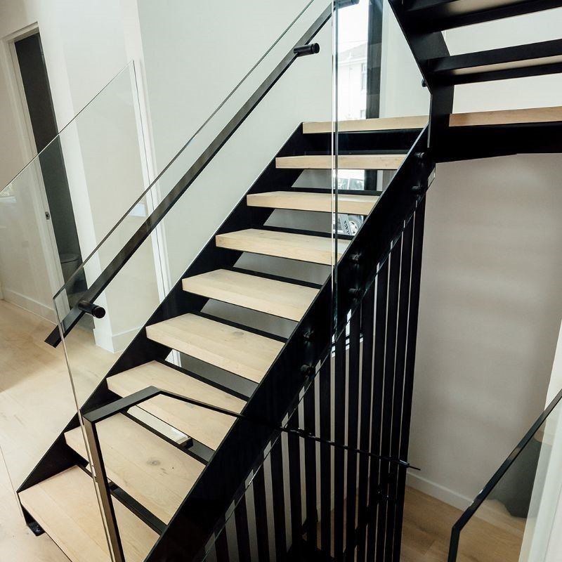Modern indoor staircase with black railings and glass panels