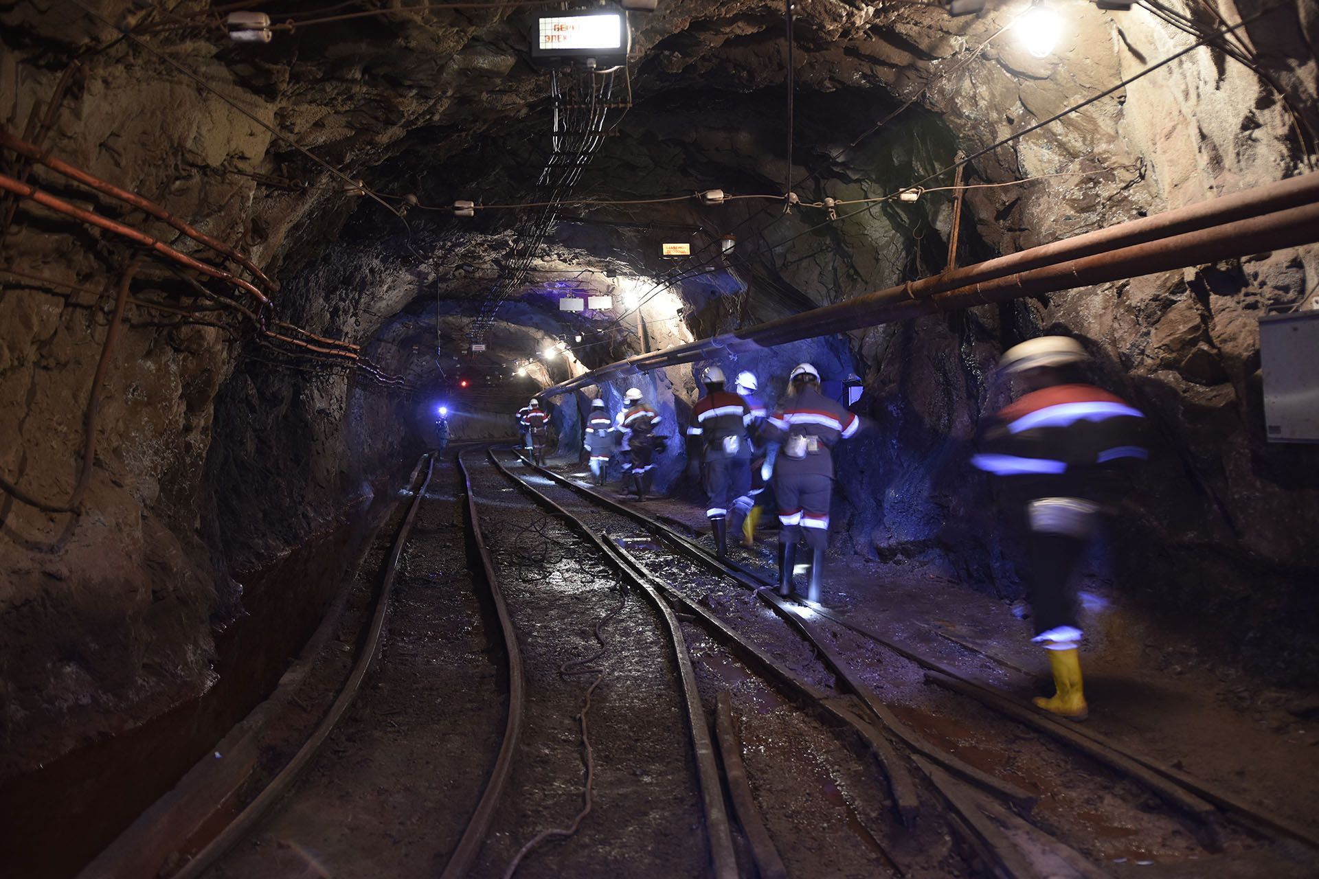 A group of people are walking down a train track in a tunnel.