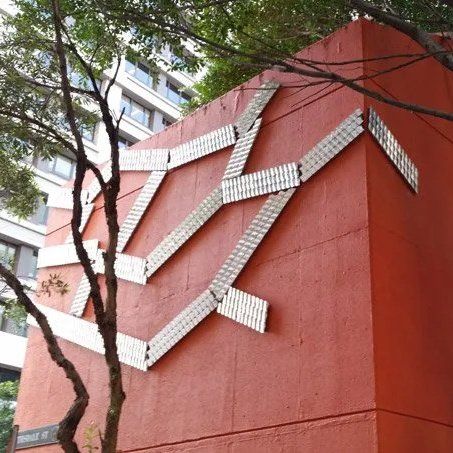 Red building wall with zigzagging white tile strips