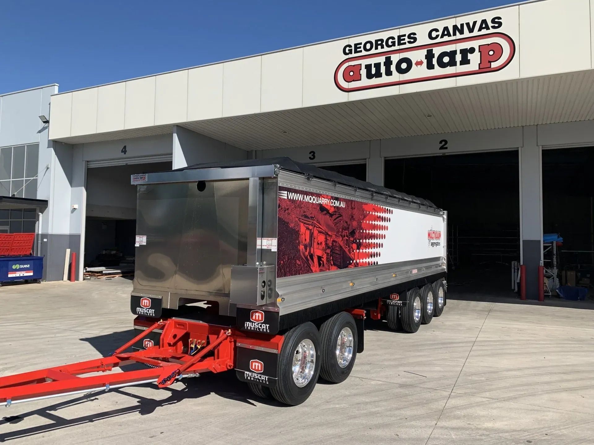 White-and-red dump trailer parked outside a warehouse