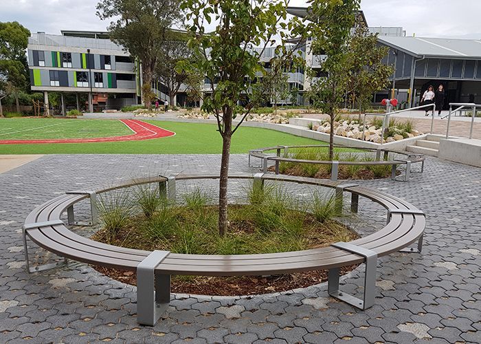 Circular bench around a small tree in a paved courtyard