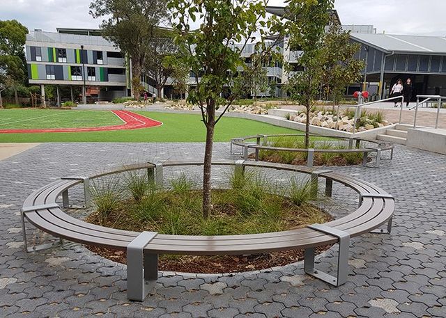 Circular bench around a small tree in a paved courtyard