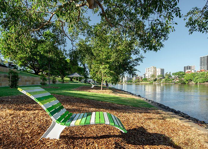 A green and white striped chair is sitting next to a river.