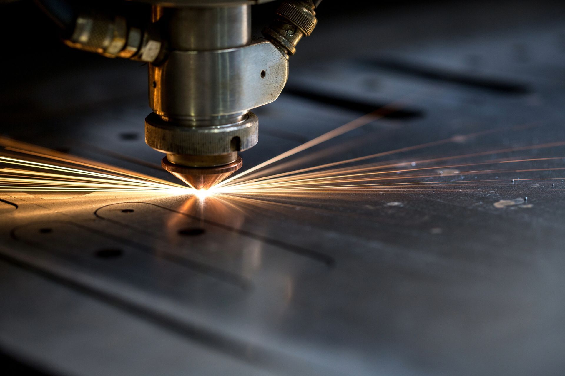 Laser cutter in action, cutting metal with sparks.