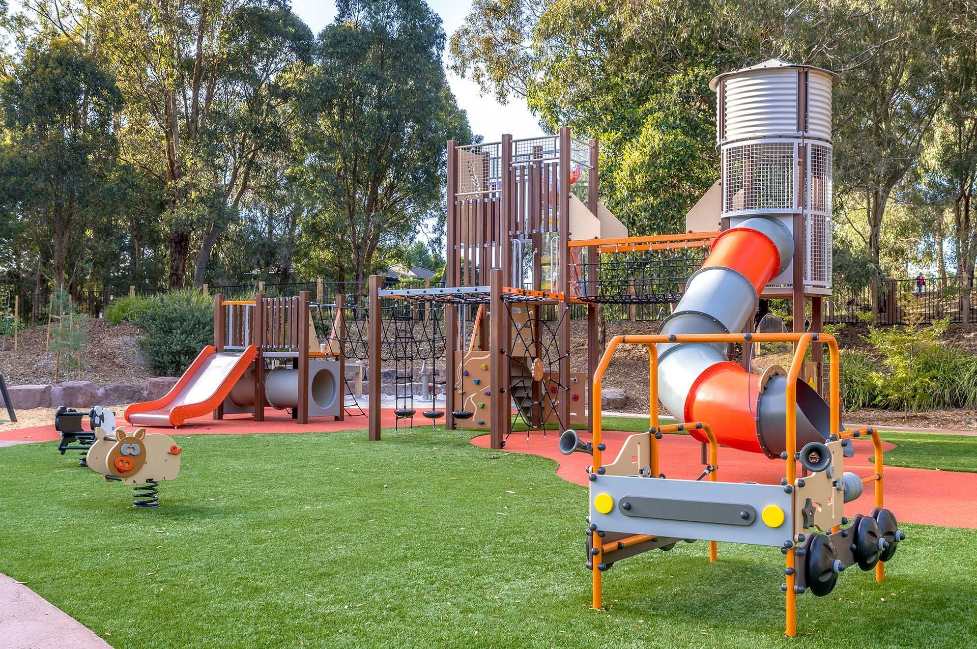 A playground with a slide , swings , and a truck in a park.