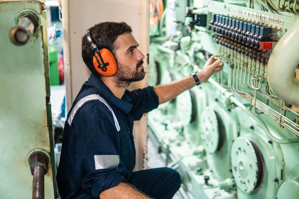 A Man Wearing Ear Muffs Is Working On A Machine — PASMA Electrical In Portsmith, QLD