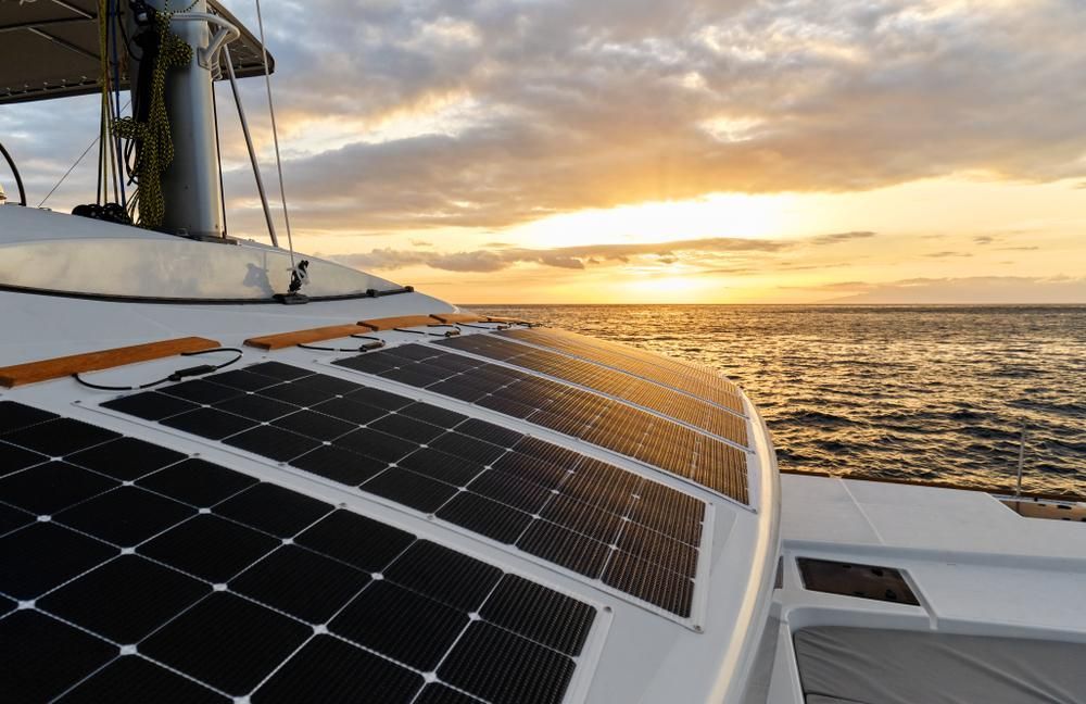 A Sailboat With Solar Panels On The Bow Is In The Ocean At Sunset — PASMA Electrical In Weipa, QLD