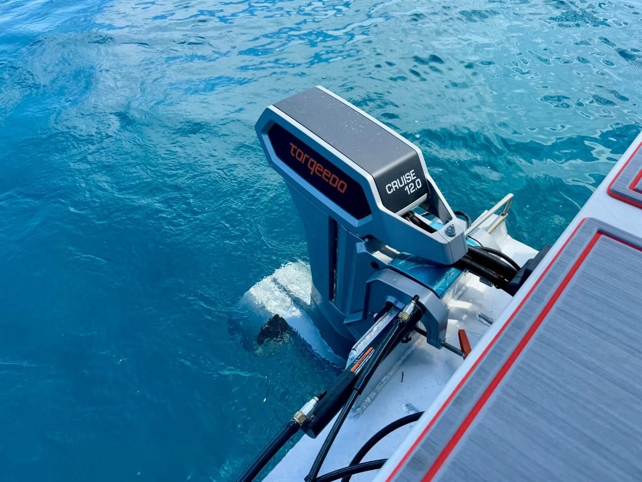 Electric boat motor in blue water. Gray and orange details on motor and boat — PASMA Electrical In Portsmith, QLD