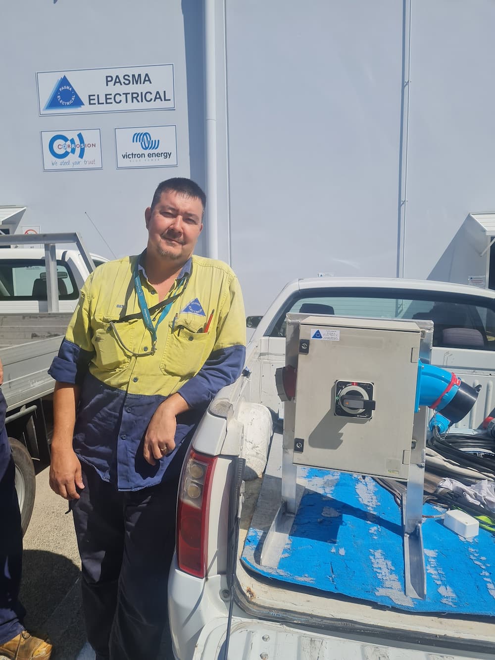 A Man In A Yellow Shirt Is Standing Next To A White Truck — PASMA Electrical In Portsmith, QLD