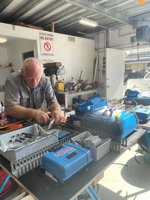 A Man Is Working On A Machine In A Garage — PASMA Electrical In Weipa, QLD