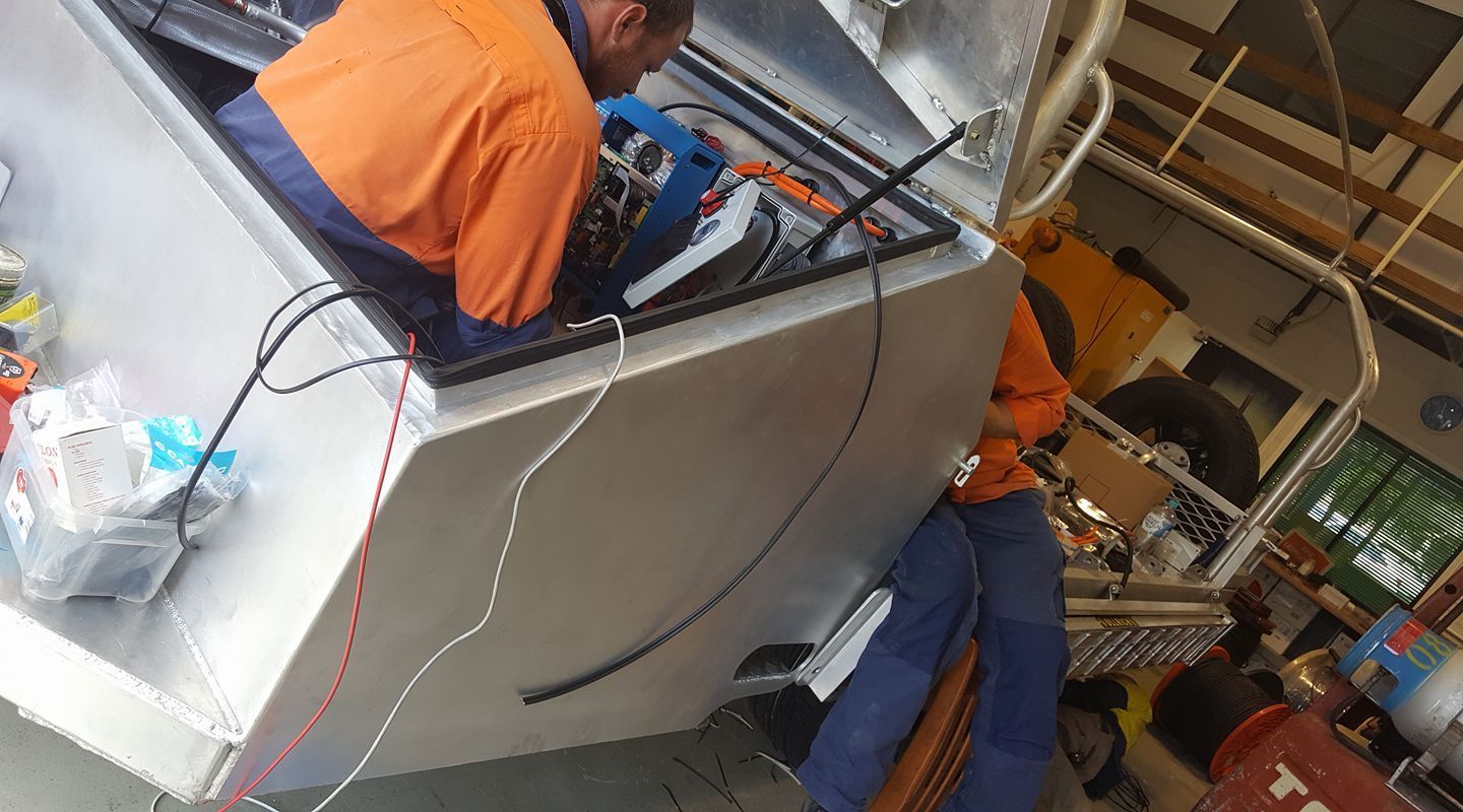A man is working on a machine in a garage — PASMA Electrical In Portsmith, QLD