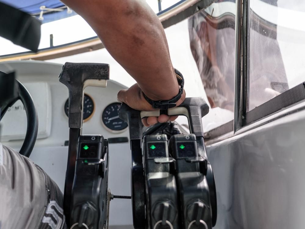 A Man Is Holding The Steering Wheel Of A Boat — PASMA Electrical In Cooktown, QLD