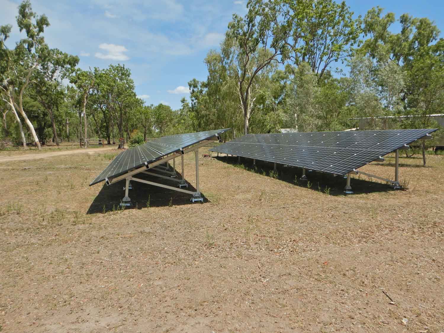 A Row Of Solar Panels In A Field With Trees In The Background — PASMA Electrical In Portsmith, QLD