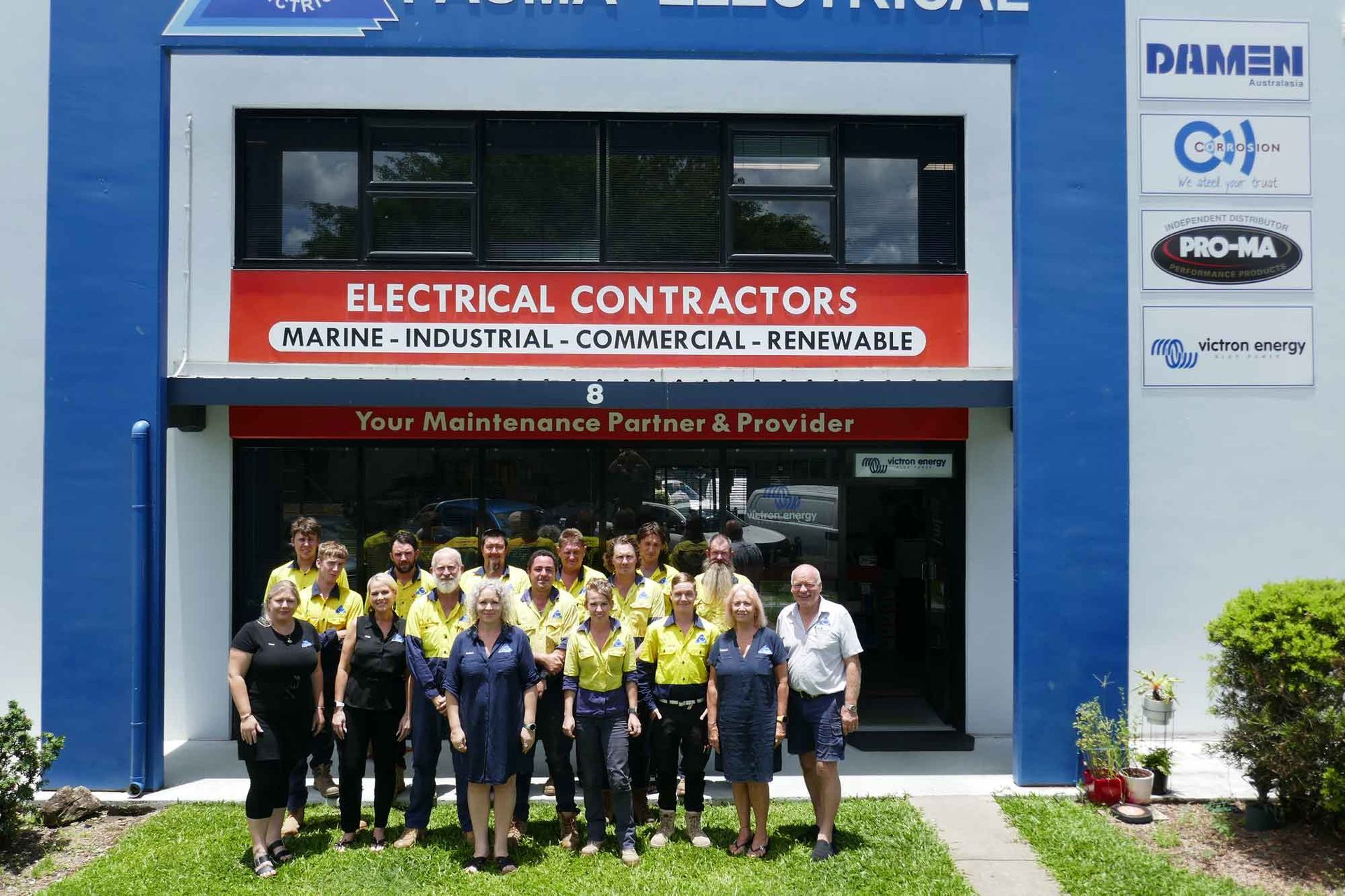 A Group Of People Standing In Front Of A Building That Says Electrical Contractors — PASMA Electrical In Portsmith, QLD