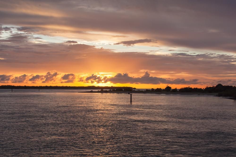 A Sunset Over A Body Of Water With A Cloudy Sky — PASMA Electrical In Weipa, QLD
