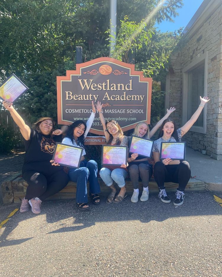 Group posing with certificates in front of the Westland Beauty Academy sign outdoors