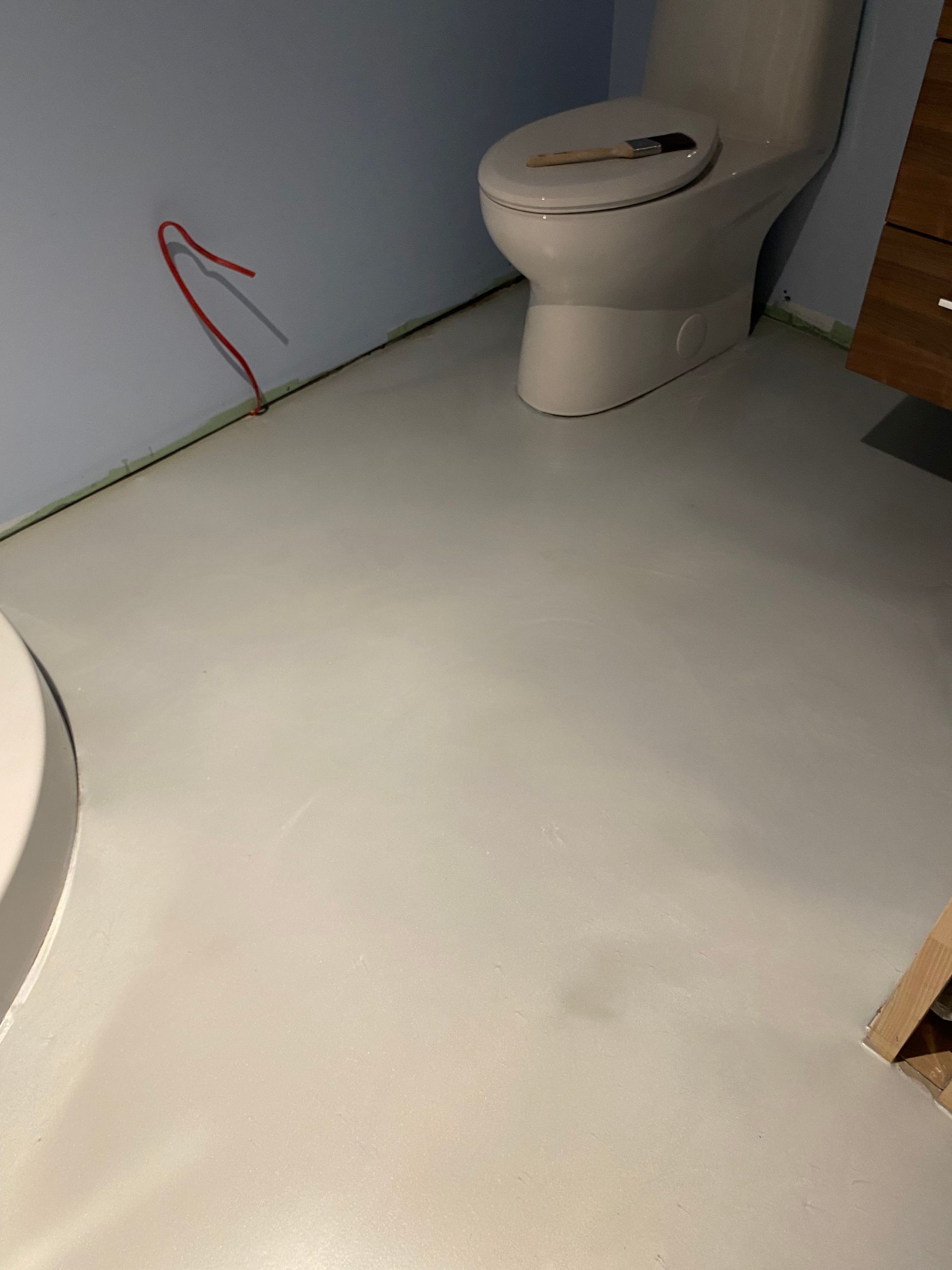 Des toilettes sont posées sur un sol blanc dans une salle de bains.