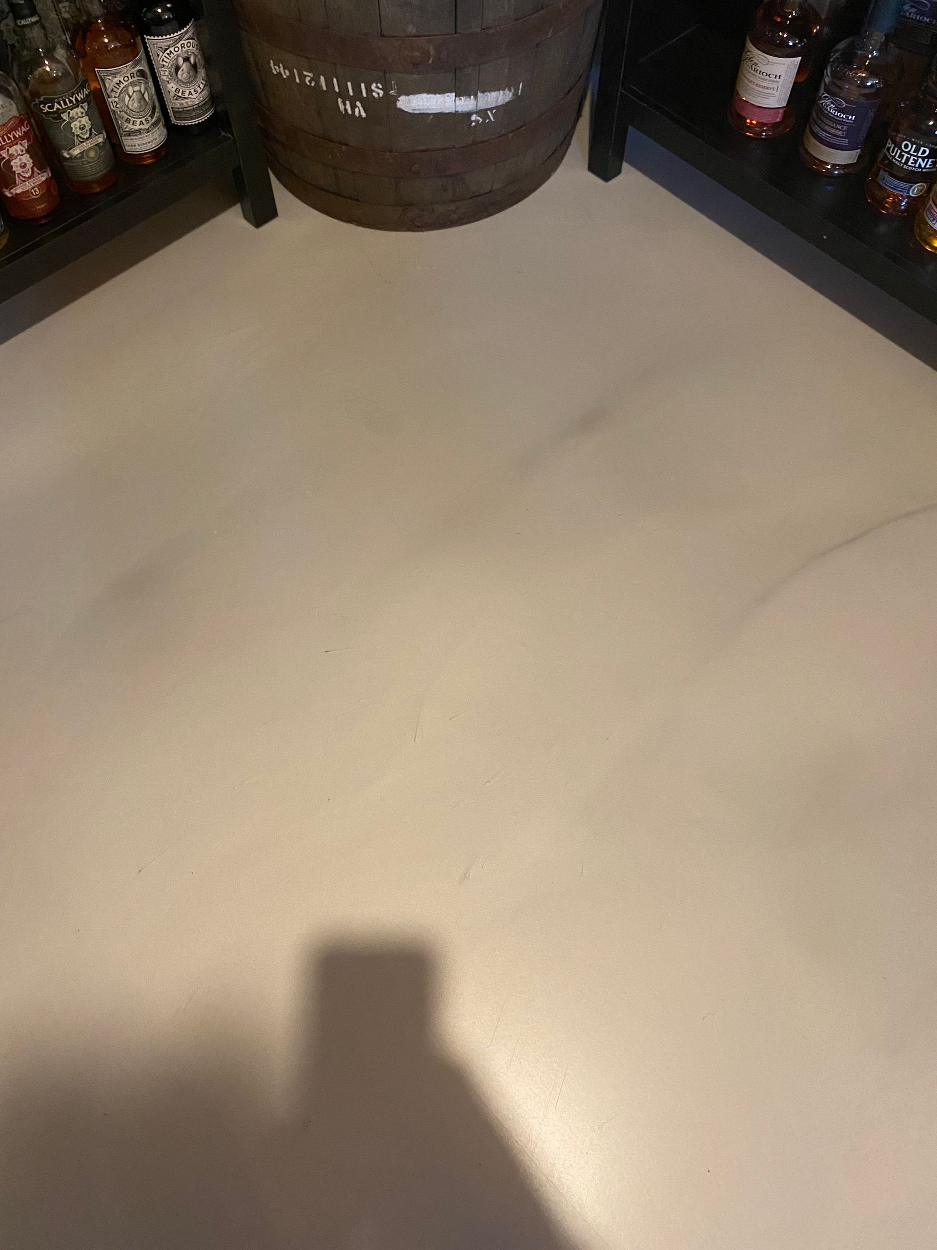 L'ombre d'une personne est projetée sur un sol blanc dans une cave à vin.