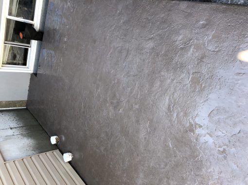 Un patio avec un sol en béton et une fenêtre.