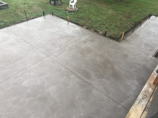 Un patio en béton est en cours de construction dans une cour arrière.