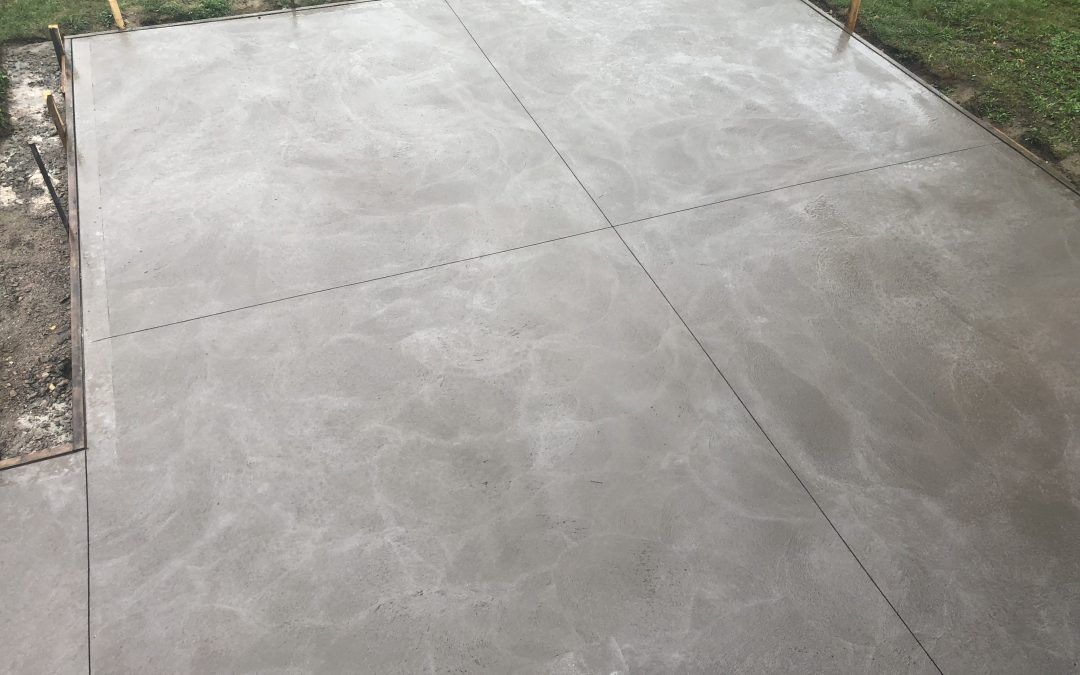 Un patio en béton est en cours de construction dans une cour arrière.