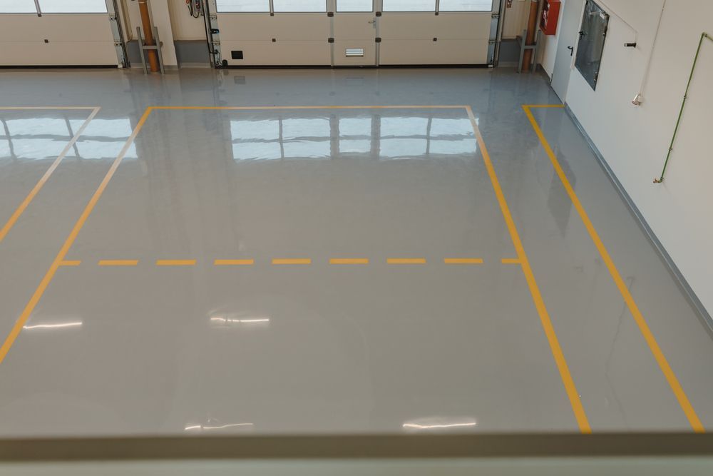 Sol gris avec des lignes jaunes dans un espace intérieur, peut-être un gymnase ou un entrepôt.