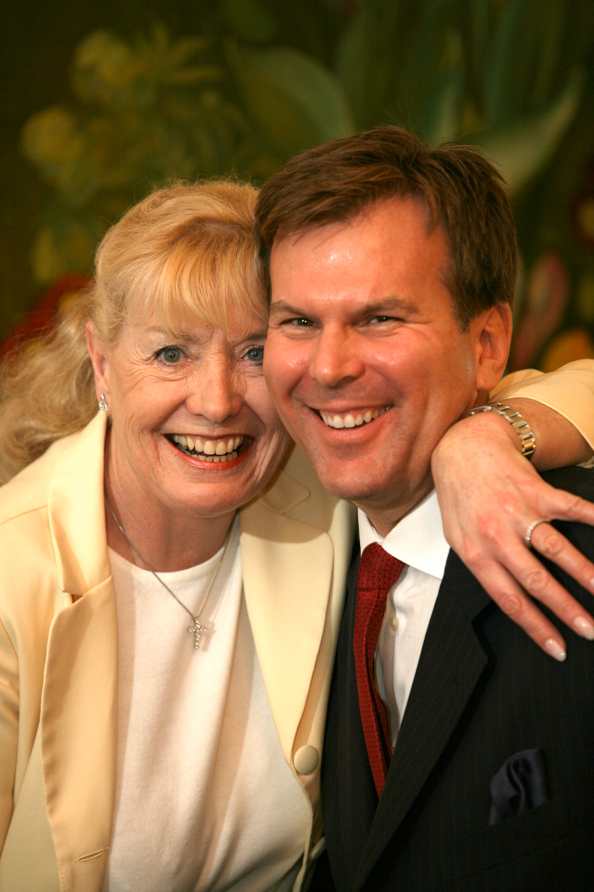 a man in a suit and tie is hugging a woman in a white jacket .