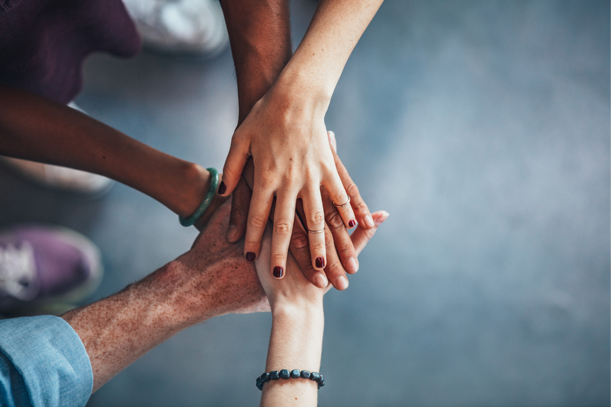 a group of people are putting their hands together in a circle .