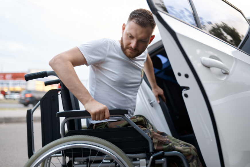 a man in a wheelchair is getting out of a car .