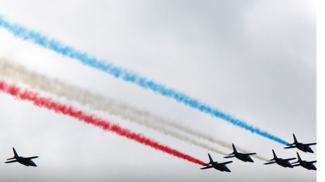 a group of fighter jets flying in formation with red white and blue smoke trails
