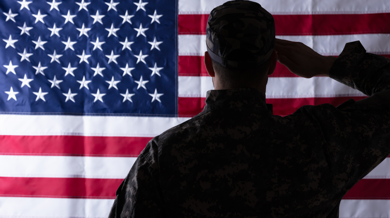 a soldier is saluting in front of an american flag .