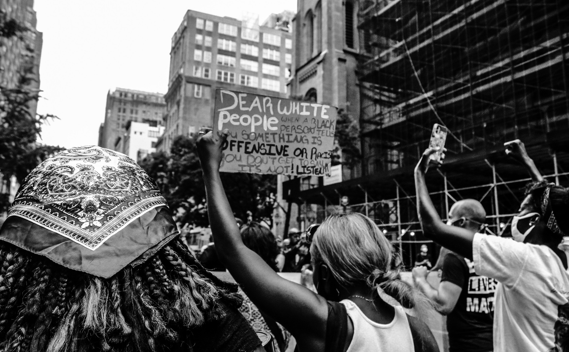 a black and white photo of a group of people holding up signs .