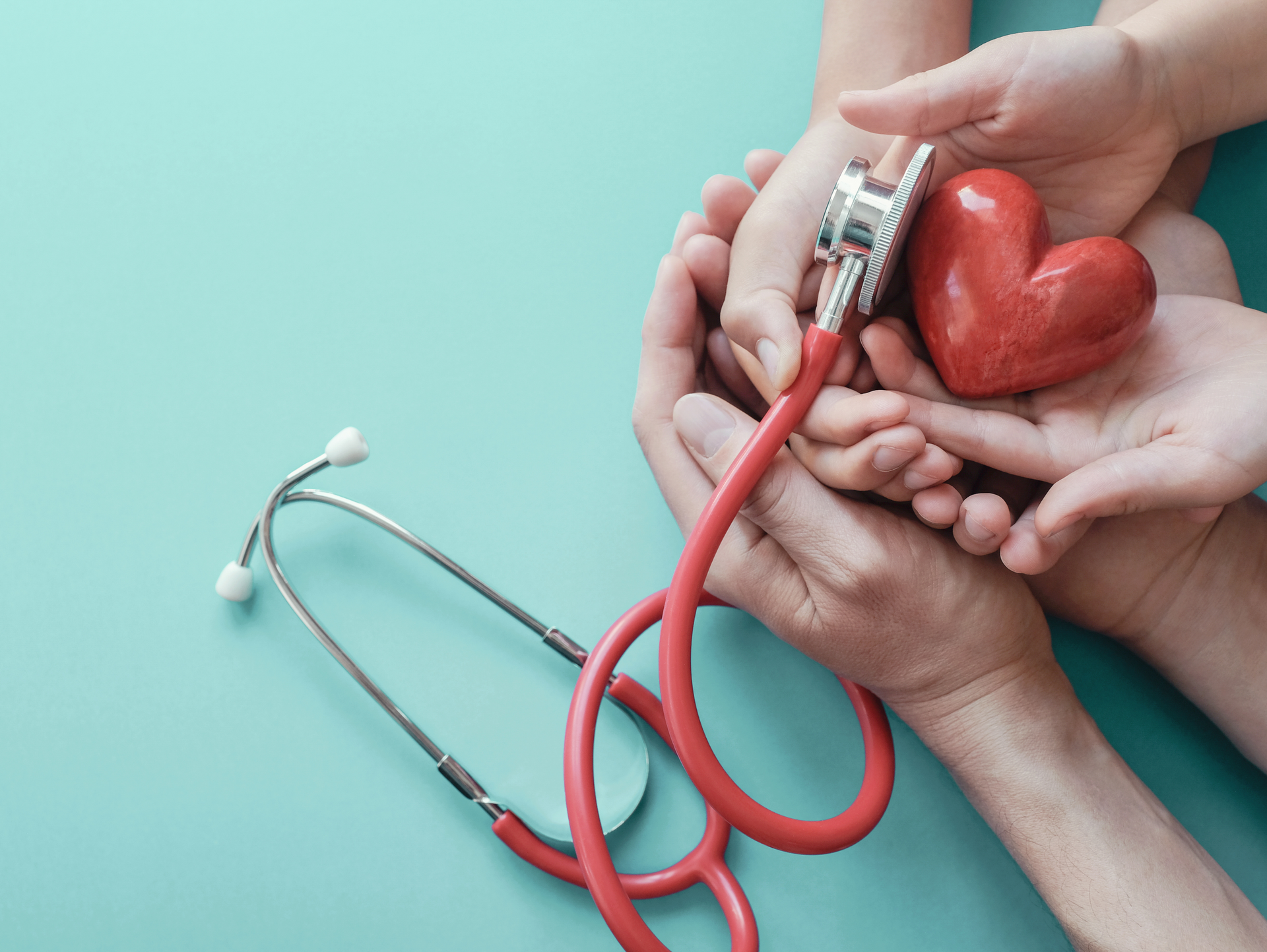 a group of people are holding a stethoscope and a heart in their hands .